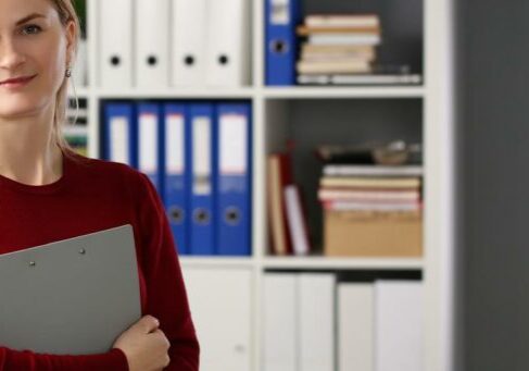 Cute blonde young office worker with documents posing in stylish outfit woman holding some papers